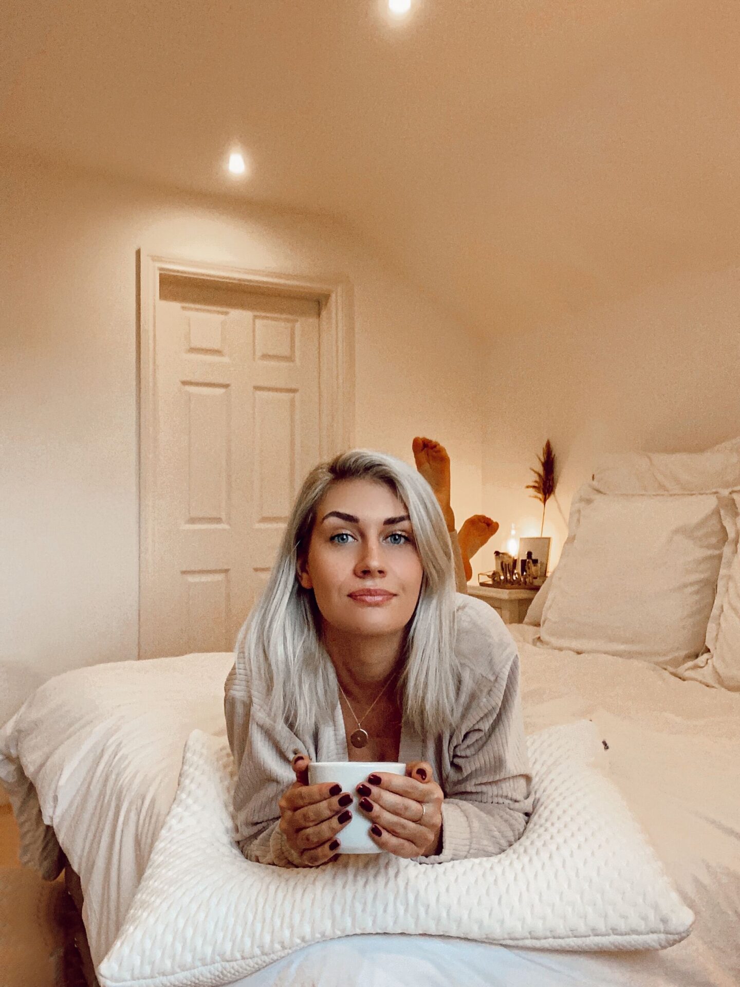 blonde_girl_laying_on_bed_with_tempur_pillow_and_a_cup_of_tea